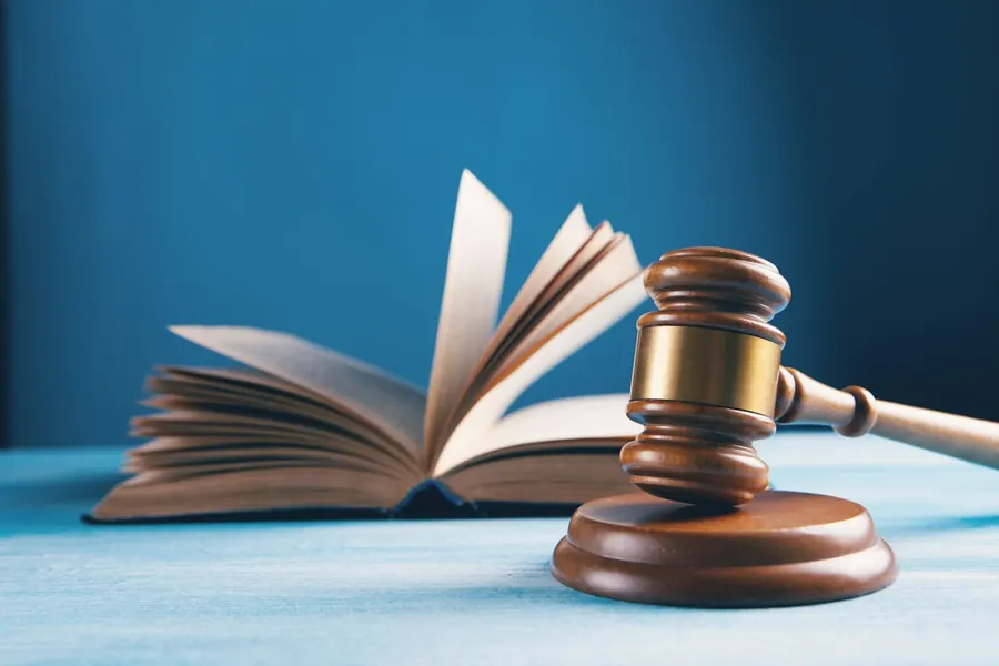 A wooden judge's gavel beside an open law book